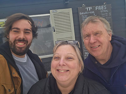 Three people smiling in front of TP Fries food stand