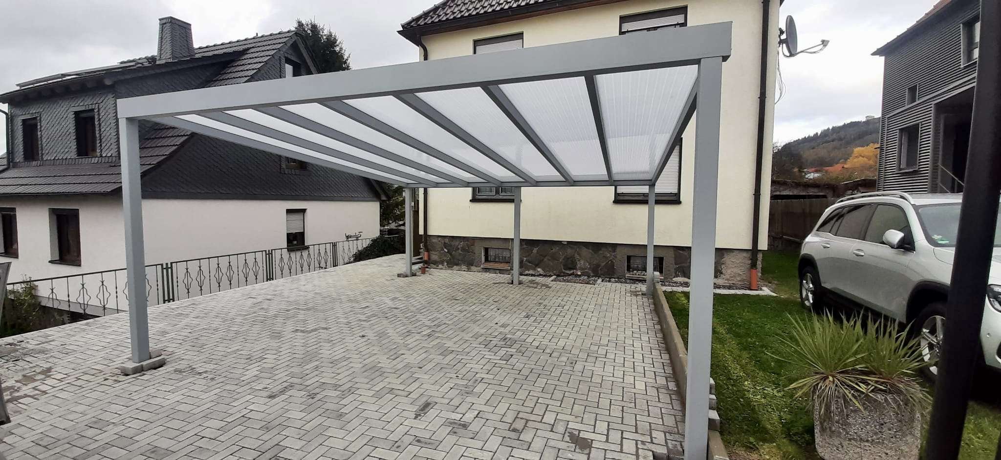 Carport mit Polycarbonat-Dach über einer Hofeinfahrt – Projekt von Pohl & Krieger