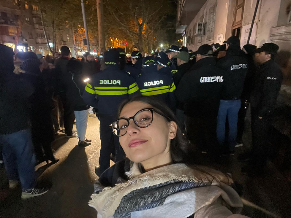 Ani Akhmeteli participe à une manifestation à Tbilissi, Géorgie. Elle est entourée de manifestant·es tenant des pancartes et drapeaux, exprimant leur opposition au Rêve géorgien et leur soutien aux libertés démocratiques.