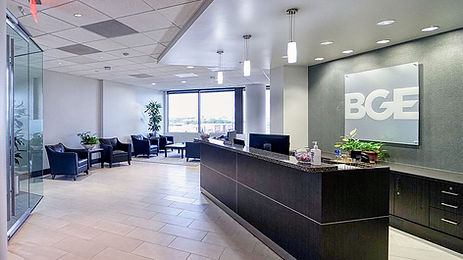Reception with a dark desk, "BGE" logo signage, and lounge seating.