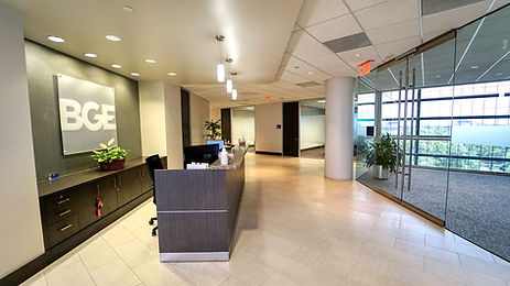 Reception with a dark desk, BGE logo signage, glass entry to the elevator lobby.
