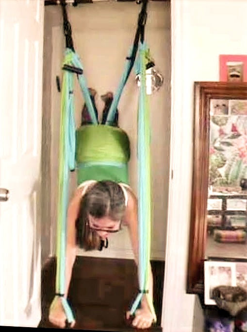 Steph in green and blue yogabody trapeze doing superman pose