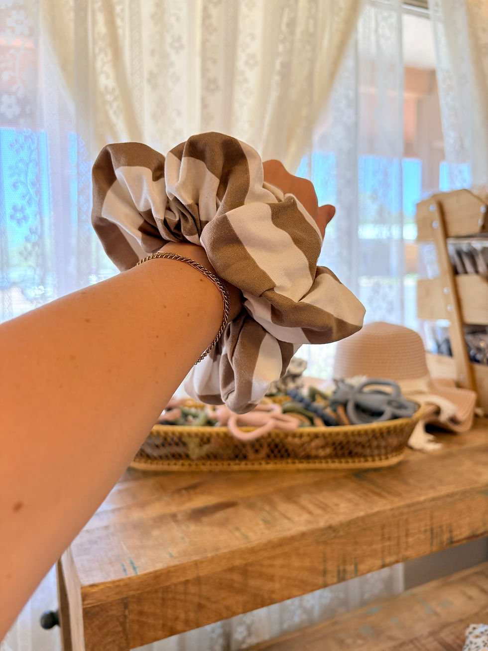 Hand with cow print scrunchie above an accessory basket