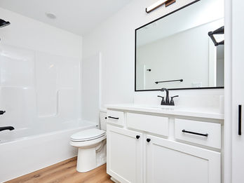 White bathroom with tub, toilet, vanity, and black fixtures