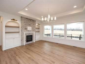 Living room with stone fireplace, built-ins, and large windows