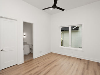 Empty room with wood floor, window, and bathroom access