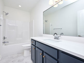 Clean modern bathroom with white shower, toilet, and dark blue vanity