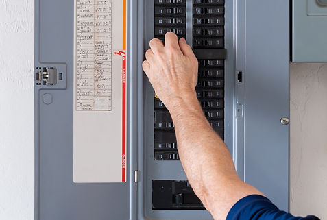 Resetting tripped breaker in residential electricity power panel. Male electrician turning