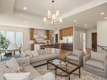 Spacious open-concept living room with light furniture and modern kitchen