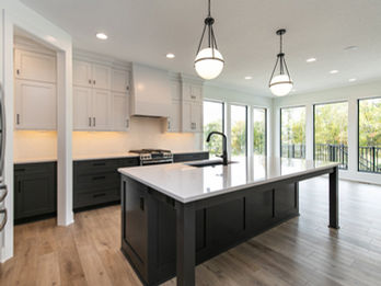 Modern kitchen with dark island, white counters, and large windows