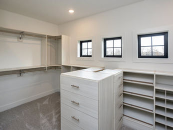 Spacious walk-in closet with shelves, drawers, windows.