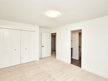 Empty room with white walls, carpet, closet, and doorways