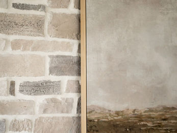 Light gray brick wall with wooden mantel and framed landscape art