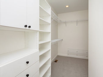Empty white walk-in closet with shelves and drawers
