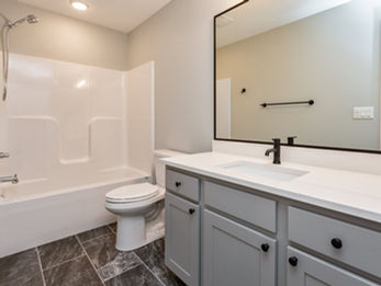 Contemporary bathroom with white tub, toilet, and gray vanity