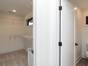 Walk-in closet with shelves next to a bathroom with a toilet