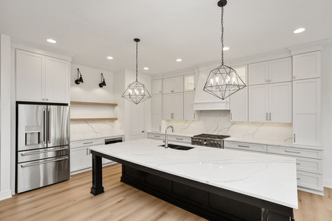 Modern kitchen with white cabinets, island, and steel fridge
