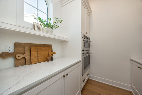 Modern kitchen pantry with white cabinets, counter, and double oven