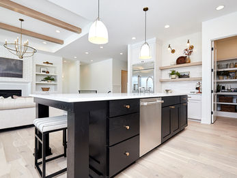 Open kitchen with dark island and adjacent living area