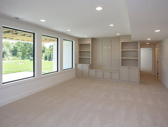 Spacious empty room with large windows and built-in shelving