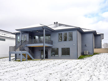 Modern gray house with a deck and snowy yard