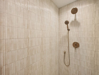 Modern shower with rainfall and handheld heads, textured tiles