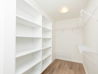 Empty closet with white shelves and wood floor
