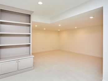 Empty room with built-in white shelves and recessed lighting