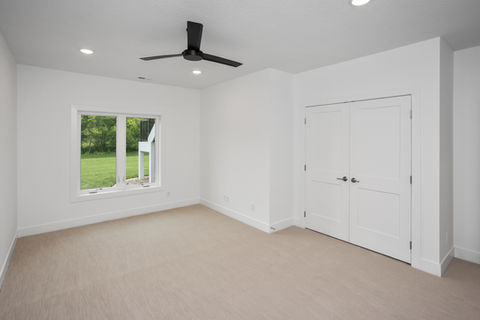 Bright empty room with window, fan, and closet doors