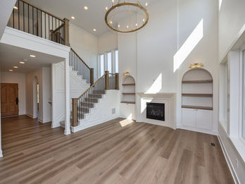Modern living room with high ceiling, grand staircase, and fireplace