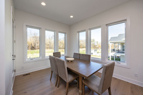 Modern dining room with wooden table, chairs, and large windows