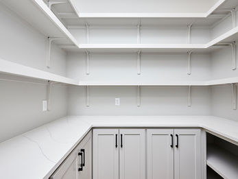 Empty white pantry with shelves and cabinets