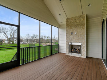 Screened porch with wooden deck, stone fireplace, and lawn view