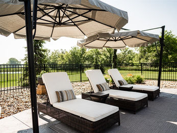 Three lounge chairs with umbrellas on a patio