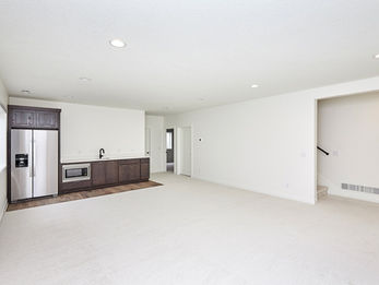 Unfurnished room with white walls, kitchenette, and stairs