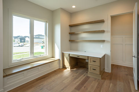 Modern home office with desk, shelves, and window seat