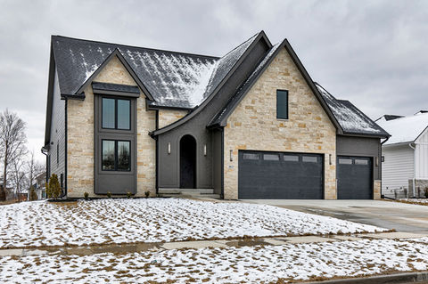 Modern house with stone and dark siding, snow on ground.