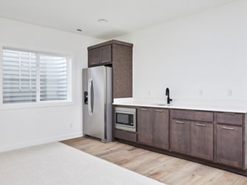 Kitchenette with stainless steel fridge, dark cabinets, sink, and window.