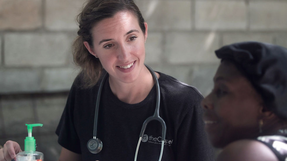 Doctor in a black shirt with a stethoscope smiles at a woman wearing a headscarf.