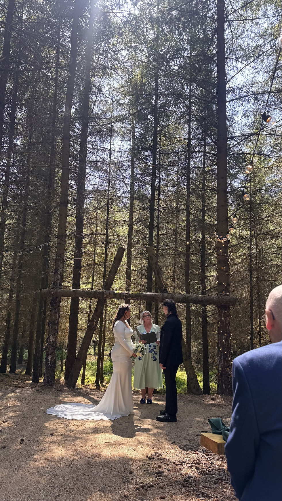 Woodland Ceremony with arch and sunlight shining through the trees