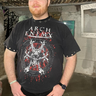 Participant wearing a studded black Arch Enemy T-shirt customized with metal details at a sustainable fashion workshop.
