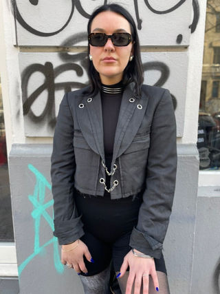 Gray blazer transformed through upcycling with metal and chain accents and cropped structure, creating an edgy, modern look.