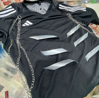 Black Adidas jersey with slashed sections and reflective silver panels, customized with chains.
