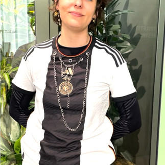 Person wearing a layered black-and-white Adidas top customized with metallic accessories and necklaces.