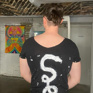 Black open-back T-shirt with a hand-painted white abstract design created at a sustainable upcycling event.