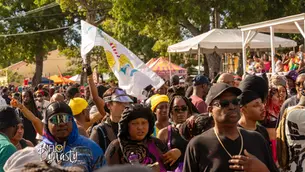Crowd gathered at St. Croix J'ouvert as a participant raises the U.S. Virgin Islands flag above the route.