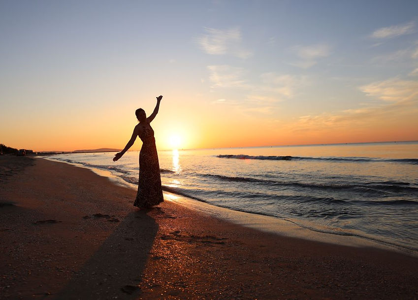 Manuela in schwungvoller Armbewegung am Sandstrand in Morgenstimmung