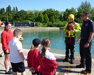A firefighter dressed in water rescue outfit talking to school children by the lake at Lee Valley White Water Centre