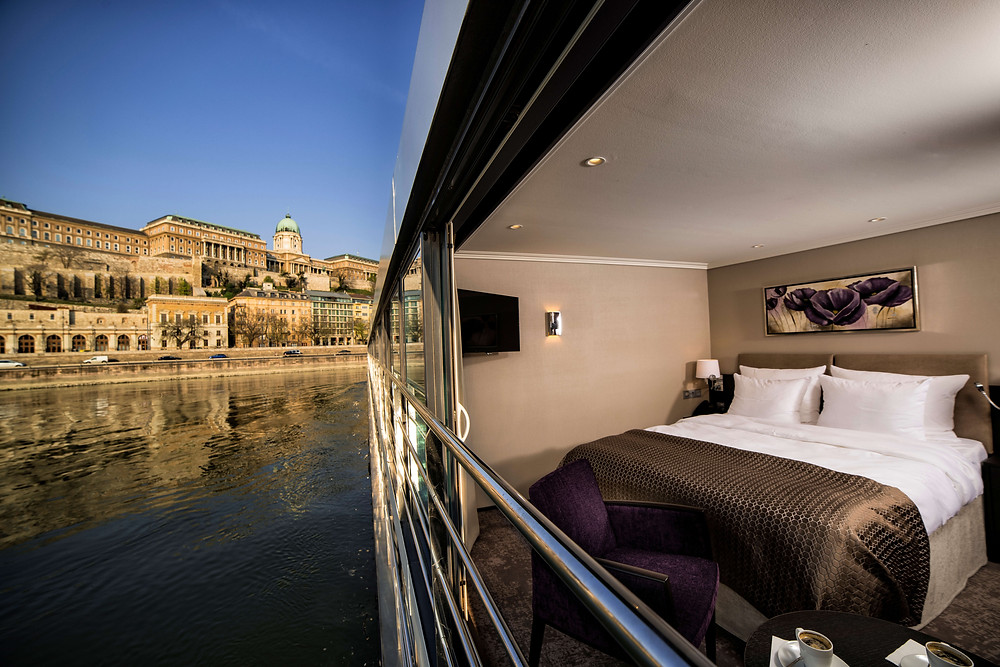 River cruise ship floating alongside architecture in city.