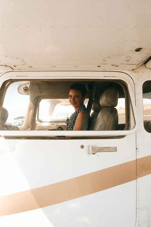 Sasha Nicole smiling through the window of Mike's Cessna at the Sauk Centre Airport